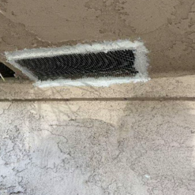 Soffit vent covered with mesh and sealed along the stucco border